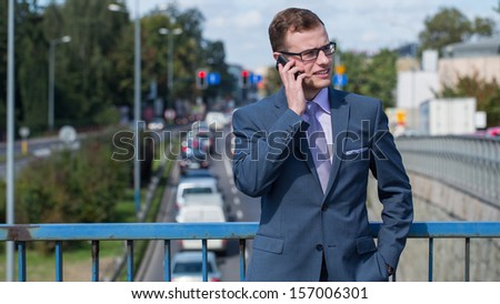Businessman with mobile phone. In the background bustling street.