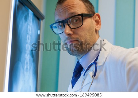 Male doctor in uniform looking at the x-ray picture of spinal column in hospital