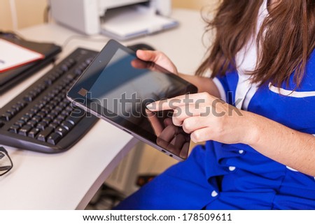 Female doctor using a tablet computer in a hospital. She is wearing blue smock