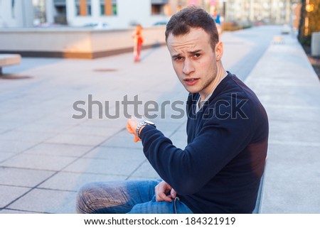 Young man is looking at his watch checking the time