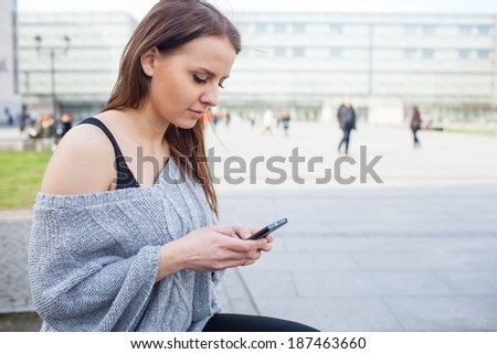 Portrait of a happy fashion woman with mobile phone. In a background office building