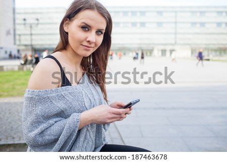 Portrait of a happy fashion woman with mobile phone. In a background office building