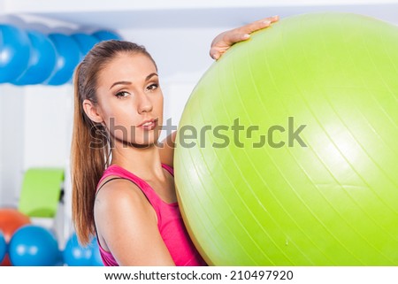Sporty woman doing fitness exercise with a green ball. In gym in sport wear