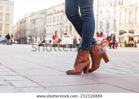 Slim model legs in blue jeans. Autumn fashion creation. On the background of city