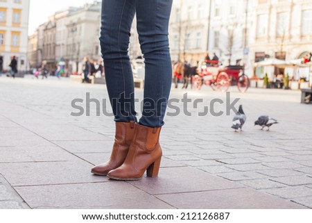 Slim model legs in blue jeans. Autumn fashion creation. On the background of city