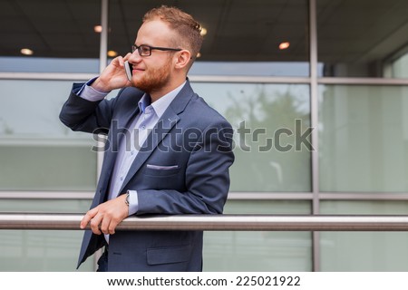Caucasian businessman outside office using mobile phone on a office block background. Copy space