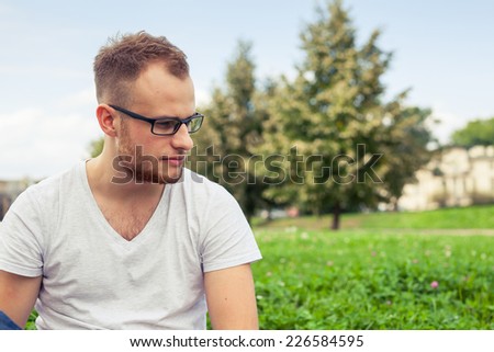 Portrait of bearded young man. Sad caucasian man on sunny summer or spring day outside in park