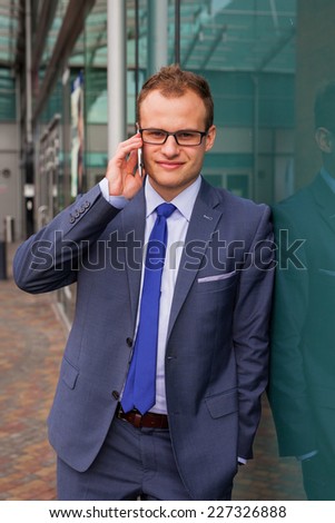 Caucasian businessman outside office using mobile phone on a office block background. Copy space.