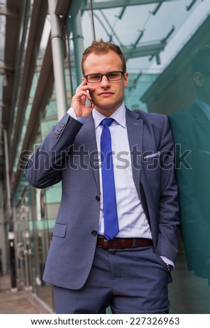 Caucasian businessman outside office using mobile phone on a office block background. Copy space.