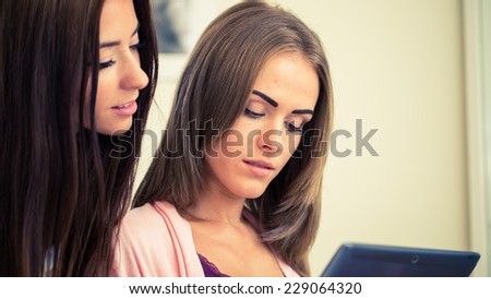 Beautiful woman showing hairstylist on a tablet examples hairstyle in hairdressing salon.