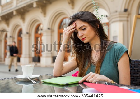 Brown hair girl sitting behind table in cafÃ?Â?Ã?Â© restaurant. She is sad