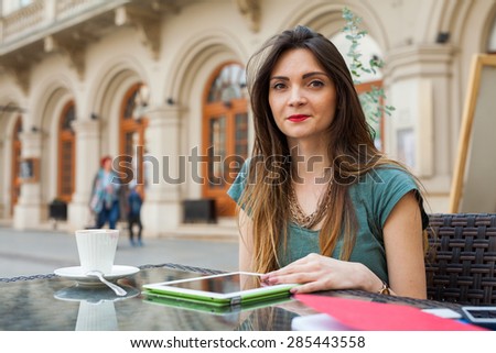 Brown hair girl sitting behind table in cafÃ?Â?Ã?Â© restaurant and using tablet