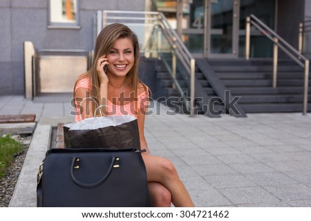 Young girl unpacking her shopping bags while calling her friend