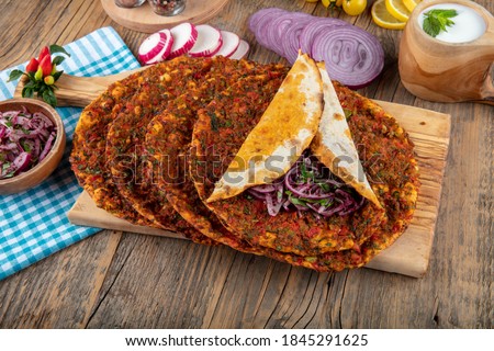 Traditional delicious Turkish foods; Lahmacun (Turkish pizza). Lahmacun traditional Turkish pizza and wraps with salad isolated on rustic wooden table.