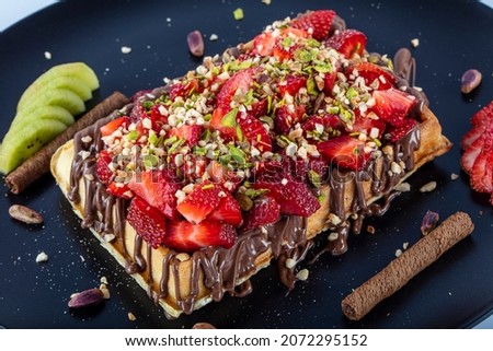 Whole wheat Belgian waffles topped with boysenberry syrup, whipped cream, walnuts and freshly chopped strawberries horizontal shot. Belgian waffles with chocolate sauce and strawberries. Stock foto © 