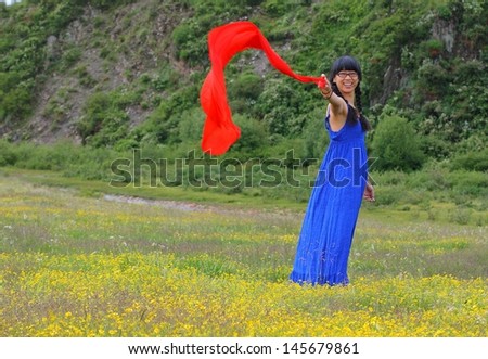 Young lady standing on grassland full of yellow flowers with a red tissue