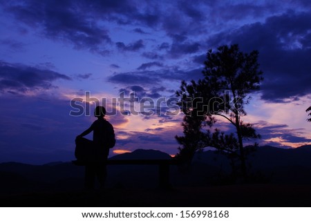 Silhouette of hiker and pine tree in beautiful sunset glow