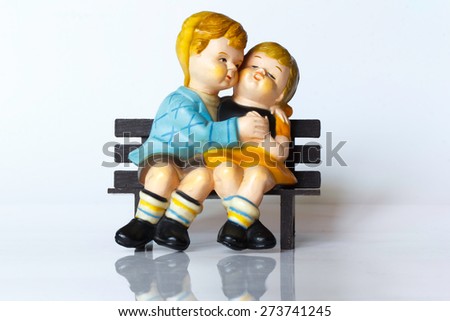 Two doll loves sitting on a chair on a white background.