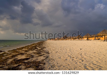 Early morning sunlight bathes Cancun Beach with ominous clouds overhead