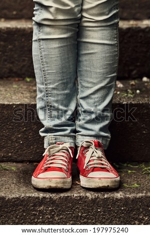 Little girl in red sneakers and jeans standing on the stairs. Making first step.