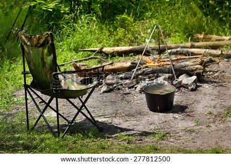 Relaxing and preparing food on campfire in camping, summer scene outdoors