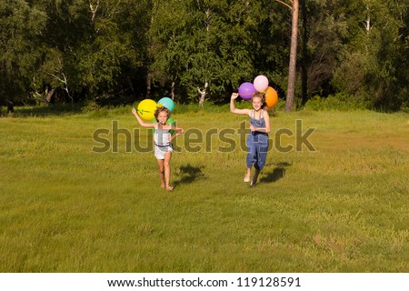 Girls ten and eight years running across the field with balloons