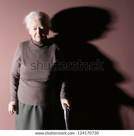 Old woman with a cane on brown background