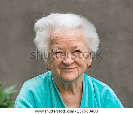 Portrait of smiling old woman on a gray background