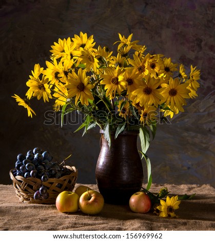 Still life with bunch of  yellow flowers (rudbeckia) in brown vase and fruits