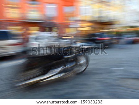 Motorcyclist in motion going down the street . Intentional motion blur