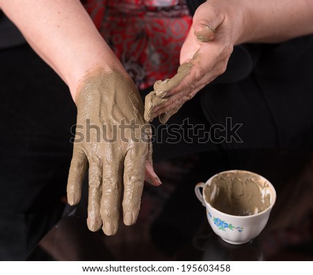 Woman applying spa cosmetic clay cream on hands