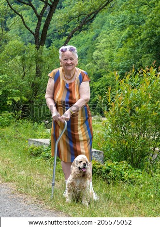 Old woman walking in summer park with a dog