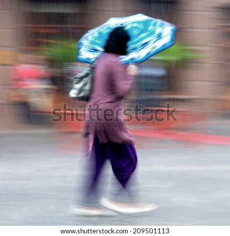 Woman walking down the street on a rainy day in motion blur