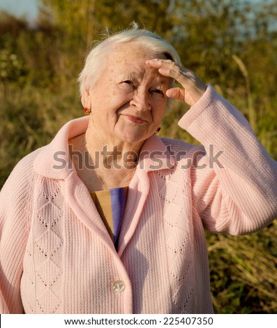 Portrait of old smiling woman in autumn park
