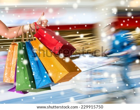 Woman holding shopping bags and gesturing thumb up at shopping mall.  Christmas and holidays concept