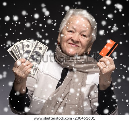 Old woman holding credit card and money. Christmas and holidays concept