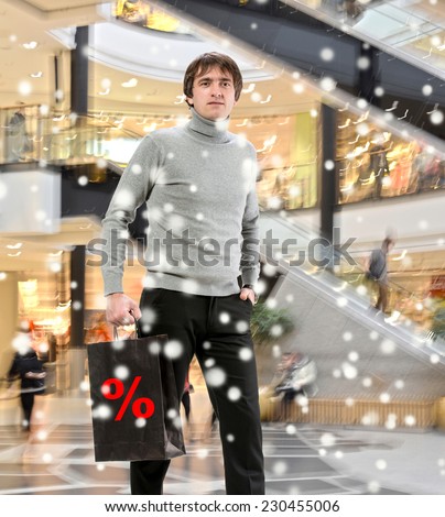 Smiling man  with shopping bag at shopping mall. Christmas and holidays concept