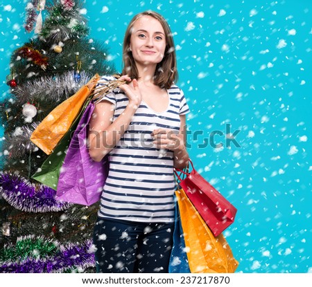 Young smiling girl with shopping bags at shopping mall. Christmas and holidays concept
