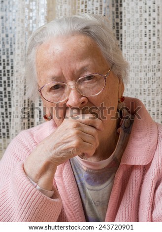 Portrait of old sad woman in glasses at home