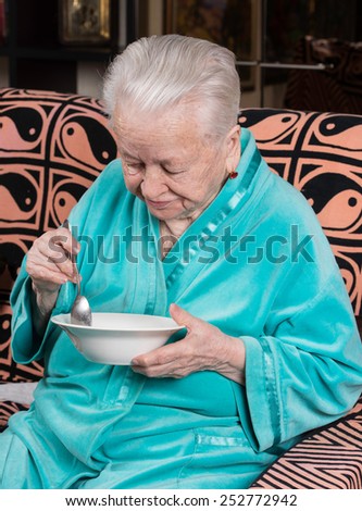 Old sad woman eating at home