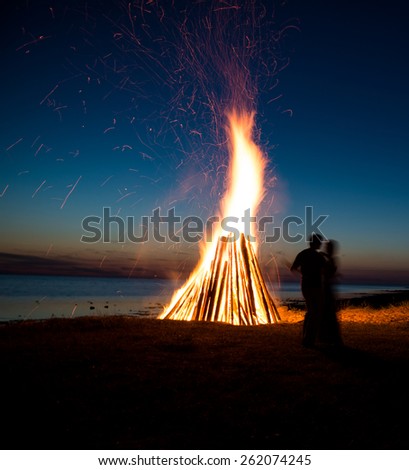 Silhouette of a couple in love against fire background. Romantic evening on the beach