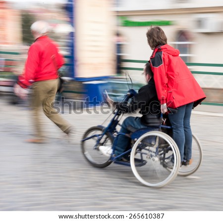 Man with disabilities in a wheelchair accompanied in motion blur