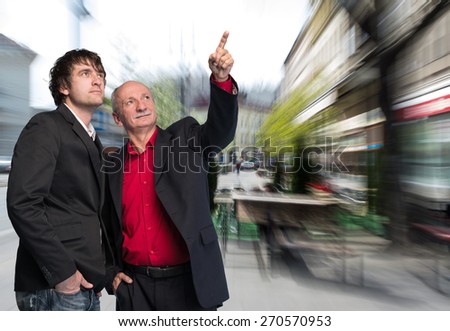 Two businessmen in the street of the city. Senior businessman pointing at something