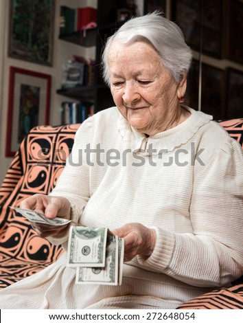 Old woman holding dollar cash money at home