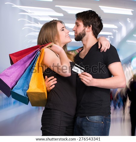 Happy couple with shopping bags at the mall. Man holding credit card
