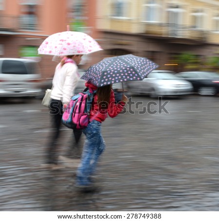 Women walking down the street on a rainy day in motion blur