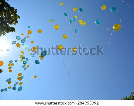 Flying yellow and blue balloons in blue sky