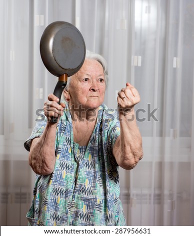 Angry old woman with a pan at home