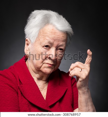 Portrait of old woman in angry gesture on a grey background