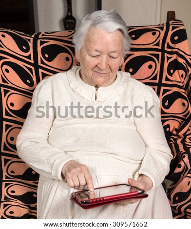 Portrait of old woman touching  digital tablet at home